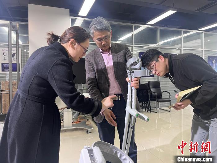 电子科技大学教授程洪(左二)就外骨骼机器人穿戴舒适度进行探讨。　王利文 摄